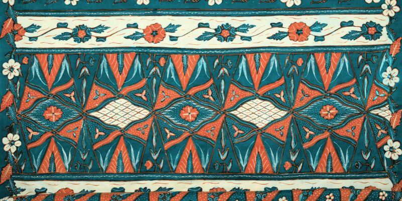 Patterned fabric in blue, brown and beige. The motifs include flowers, leaves, triangles and diamonds in repeating rows.