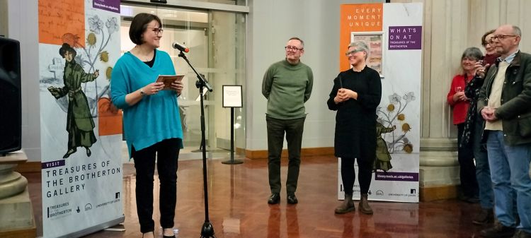 An image from the Part of the Furniture exhibition launch event. A speaker is stood at a microphone speaking to a group of people.