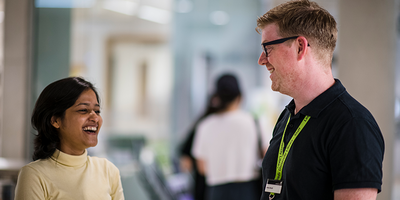 A member of Library staff helping a smiling student in the Laidlaw Library.