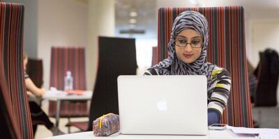 A student working at a desk using a laptop computer