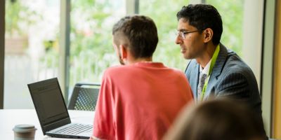 A staff member helping a student complete work on their laptop