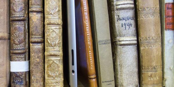 A row of books and an ipad on a shelf