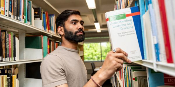 A student choosing a book from a bookshelf.