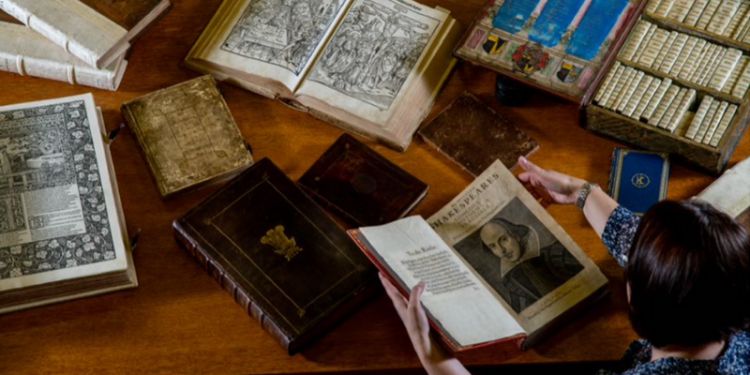 Books from Special Collections open on a table with someone reading them.