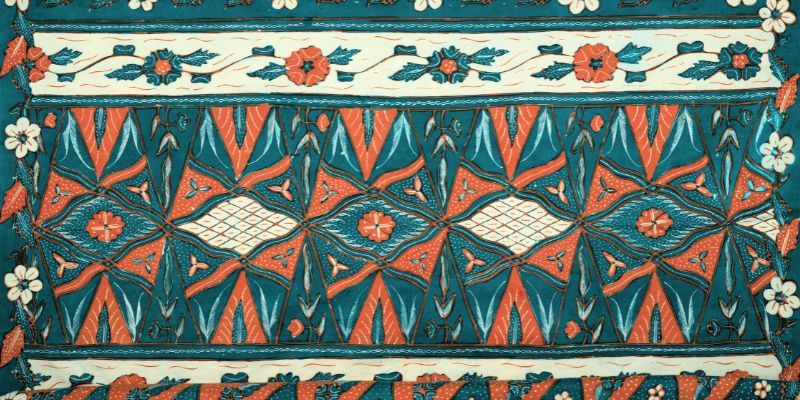 Patterned fabric in blue, brown and beige. The motifs include flowers, leaves, triangles and diamonds in repeating rows.
